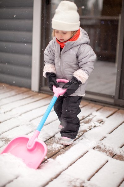 可爱的小孩在冬天的大衣铲雪