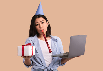 悲伤的亚洲女人在帽子里拿着礼物盒和笔记本电脑