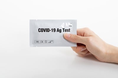 手放在白色背景上的COVID-19家用快速检测试剂盒。