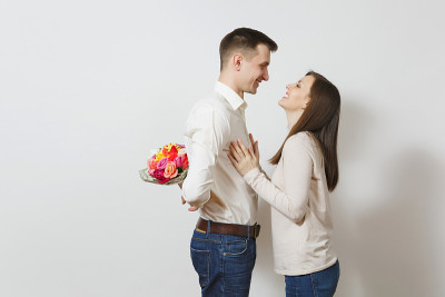 夫妇在爱。女人回头看躲在他后面的男人，一束美丽的玫瑰花孤立在白色的背景上。情人节、国际妇女节生日节日