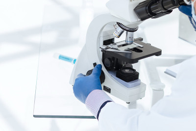 科学家生物学家戴着防护面具透过显微镜观察