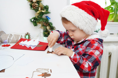 child girl in Santa hat making christmas card from