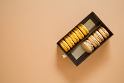 俯视图马卡龙法国蛋糕或马卡龙杏仁饼干，柠檬和咖啡马卡龙在棕色背景。