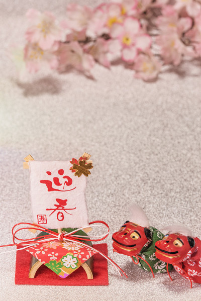 日本新年贺卡与红色的手写意为欢迎春天与可爱的民间动物雕像的两只狮子石脉，宣纸和竹子装饰在闪闪发光的银
