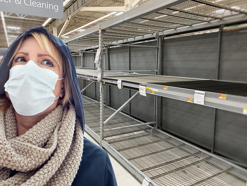 年轻女子戴着医用口罩在杂货店的空过道里