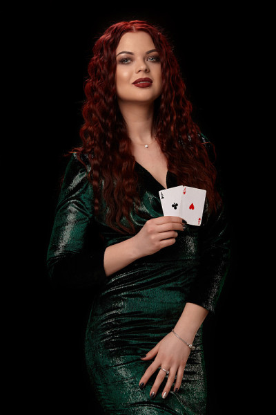 性感的红发女人摆姿势与扑克牌在她的手中，在黑色的背景