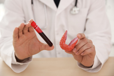 医生拿着塑料模型的甲状腺和试管与uk血液样本在木桌，近距离