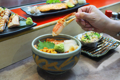 一碗新鲜三文鱼片、扇贝、海胆、育仓和蟹肉炒饭，配上腌生姜和芥末。