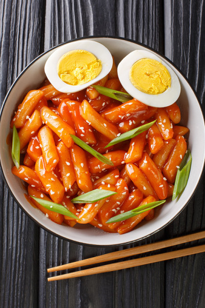 韩国辣味年糕与鸡蛋特写在碗里。垂直的俯视图