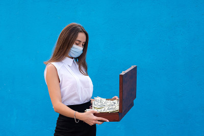 美丽的女商人因为感染了冠状病毒戴着医用口罩，手里拿着美元