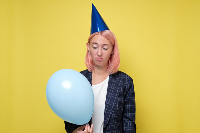 戴着生日帽，带着噪音器的女人。女孩不想庆祝她的生日。
