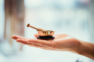 婴儿唱碗:女人手里的小金属唱碗。模糊的背景。