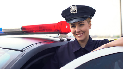 戴着服务帽的漂亮女警察对着镜头微笑，保护城市的女人