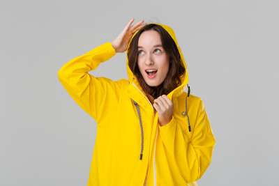 微笑的黑发女孩穿着黄色雨衣。准备好迎接坏天气吧。