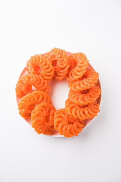 在白色的背景上，用白色的陶瓷盘子盛着印度甜的Imarti或Jalebi