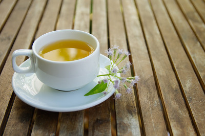 一杯茶，陶瓷盘子上放着几朵野雏菊花