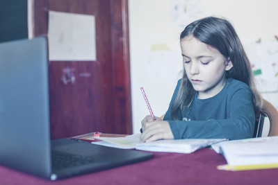可爱的小学生女孩做家庭作业隔离在冠状病毒流行