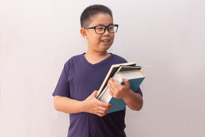 亚洲男孩拿着书准备上学