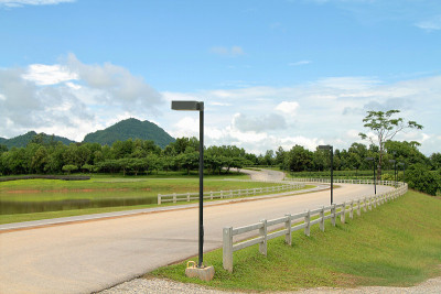 弯曲的道路与白色的尖桩篱笆和蓝色的天空在农田
