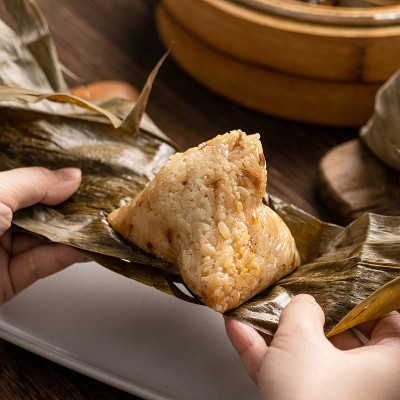 吃粽子-端午节粽子年轻的亚洲妇女吃中国传统食物在家里的木桌庆祝。