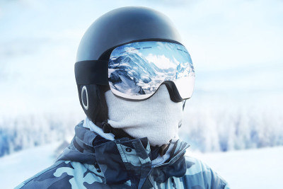 一个男人的滑雪镜的特写与雪山的倒影。蓝天下的人。戴着滑雪眼镜。冬季运动。