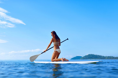 休闲的水上运动。女人在冲浪板上划桨。夏天