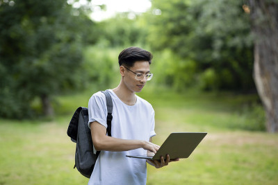 教育和科技。男亚裔学生在校园里使用笔记本电脑