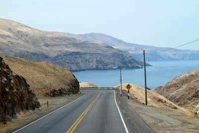 空旷的道路，背景是群山和大海