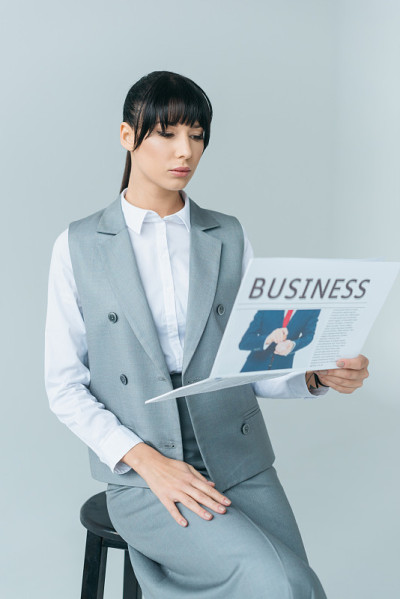 女商人独自坐在椅子上看商业报纸