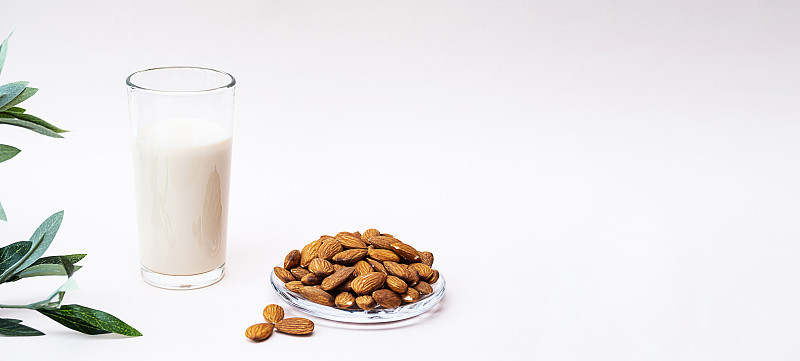 杏仁牛奶与杏仁在轻背景与复制空间。不含乳制品和乳糖的坚果奶，健康饮食，素食和饮食理念。