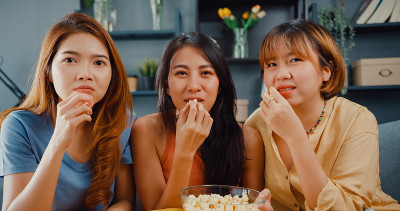 有吸引力的亚洲可爱的淑女女孩团体积极的高兴的高兴的与随意有乐趣，享受看在线电影娱乐在客厅的沙发在家里