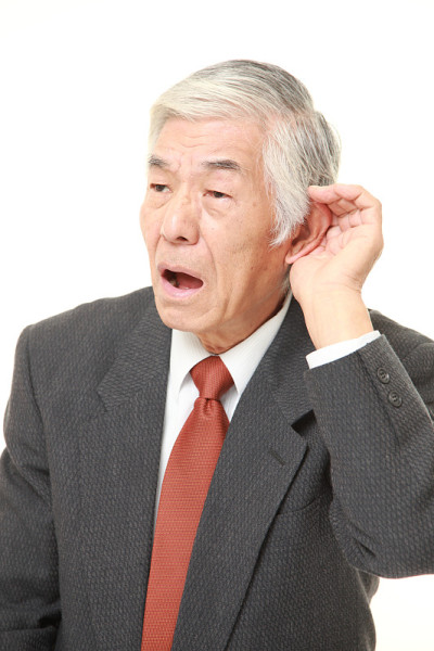 日本资深商人把手放在耳朵后面，仔细听着