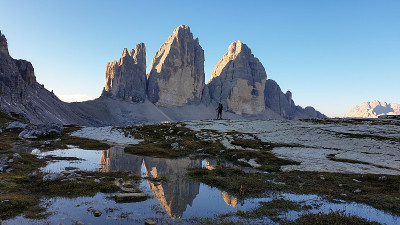 一名男子正在欣赏意大利Dolomites地区的Drei Zinnen山。群山倒映在小桨里。荒凉和原始