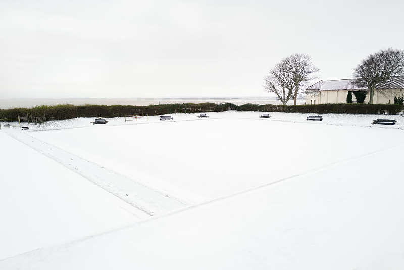 在一个室外保龄球场周围的长椅在淡季被雪覆盖。