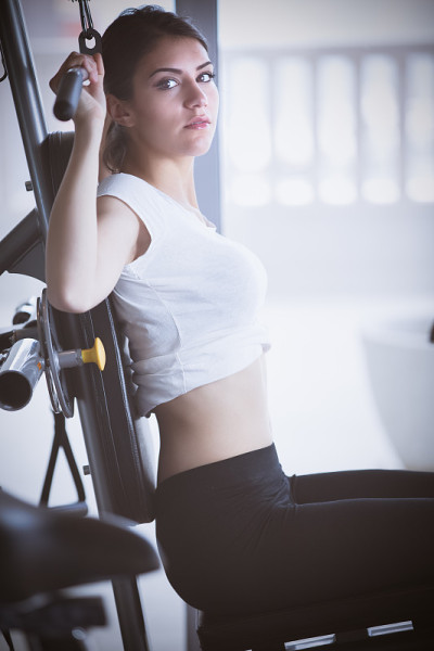 女子在健身房进行举重训练。在下拉器械上锻炼