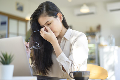 疲惫和压力的商业妇女头痛在咖啡馆使用笔记本电脑