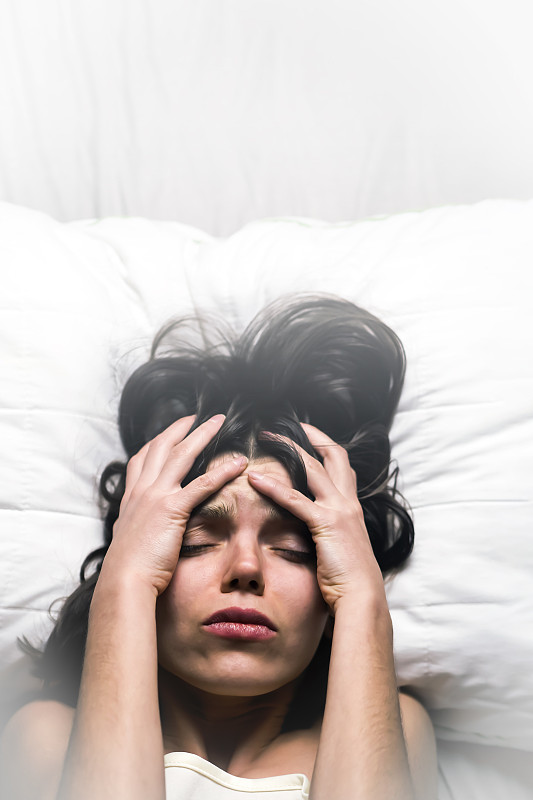 年轻的女孩带着惊恐的表情从床上的噩梦中醒来。
