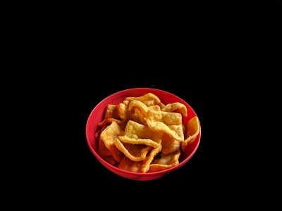 碗与猪肉皮在黑色的背景。垃圾食品的概念