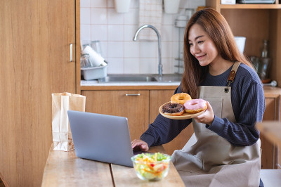 一名女视频博主在厨房烹饪食物，并拍摄为在线学习烹饪课概念