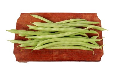 菜豆放在木砧板上，孤立在白色背景上