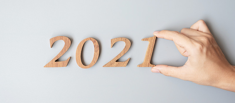 商人手改变木数字2020到2021在灰色背景。计划，财务，决议，战略，解决方案，目标，业务和新年假期