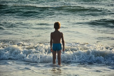 男孩站在海里，望着大海