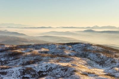 白雪覆盖着辽阔的高原，夕阳柔和的金色光芒照亮了大地