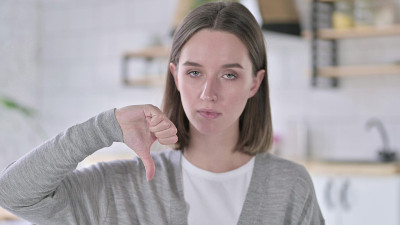 沮丧的年轻女子的肖像显示拇指向下
