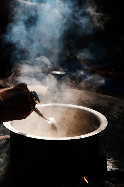 女人的手和戒指混合神秘的东西在一个锅与蒸汽在黑暗的背景