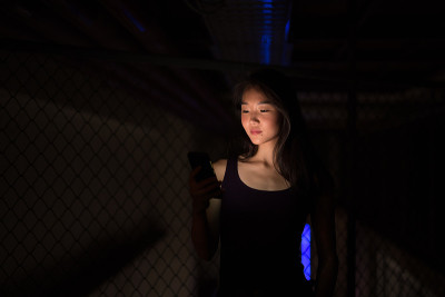 美丽的亚洲女人晚上在户外使用手机