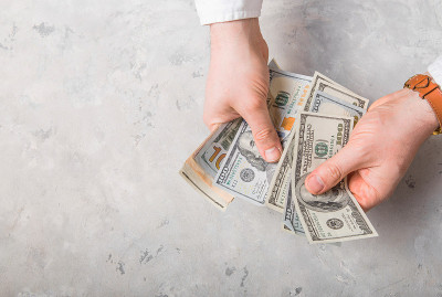 男人在办公室用手数现金。近距离的男人的手在数美元。开始投资资本。在信用公司办公室进行货币计算。俯视图