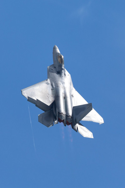 F-22猛禽在美丽的光，与加力燃烧器和凝结尾形成在翼尖