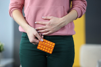 女人拿着药丸在家里抱着小腹特写
