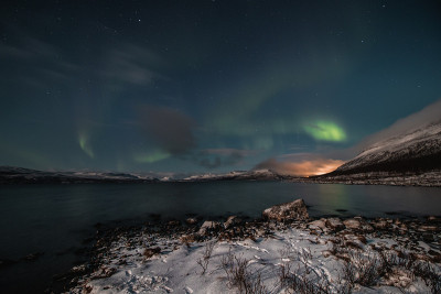 在芬兰拉普兰的Kilpisjarvi，在一个无云的夜晚，北极光扫过一个大湖。绿莹莹的北极光在天空中舞